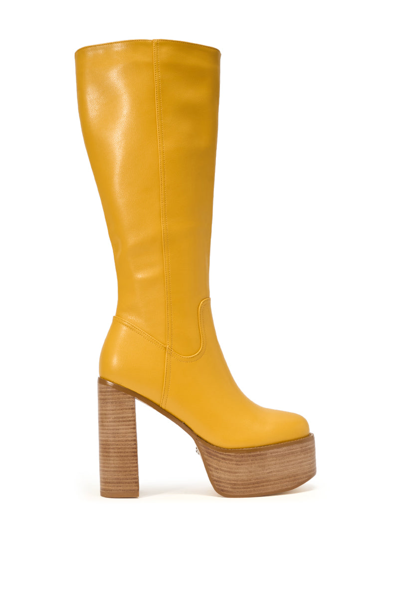 The AZALEA WANG LANDRY Yellow PU Wood Stack Platform Boot is a knee-high, faux leather boot with a chunky block heel and wooden platform, shown in profile against a plain white background. 3