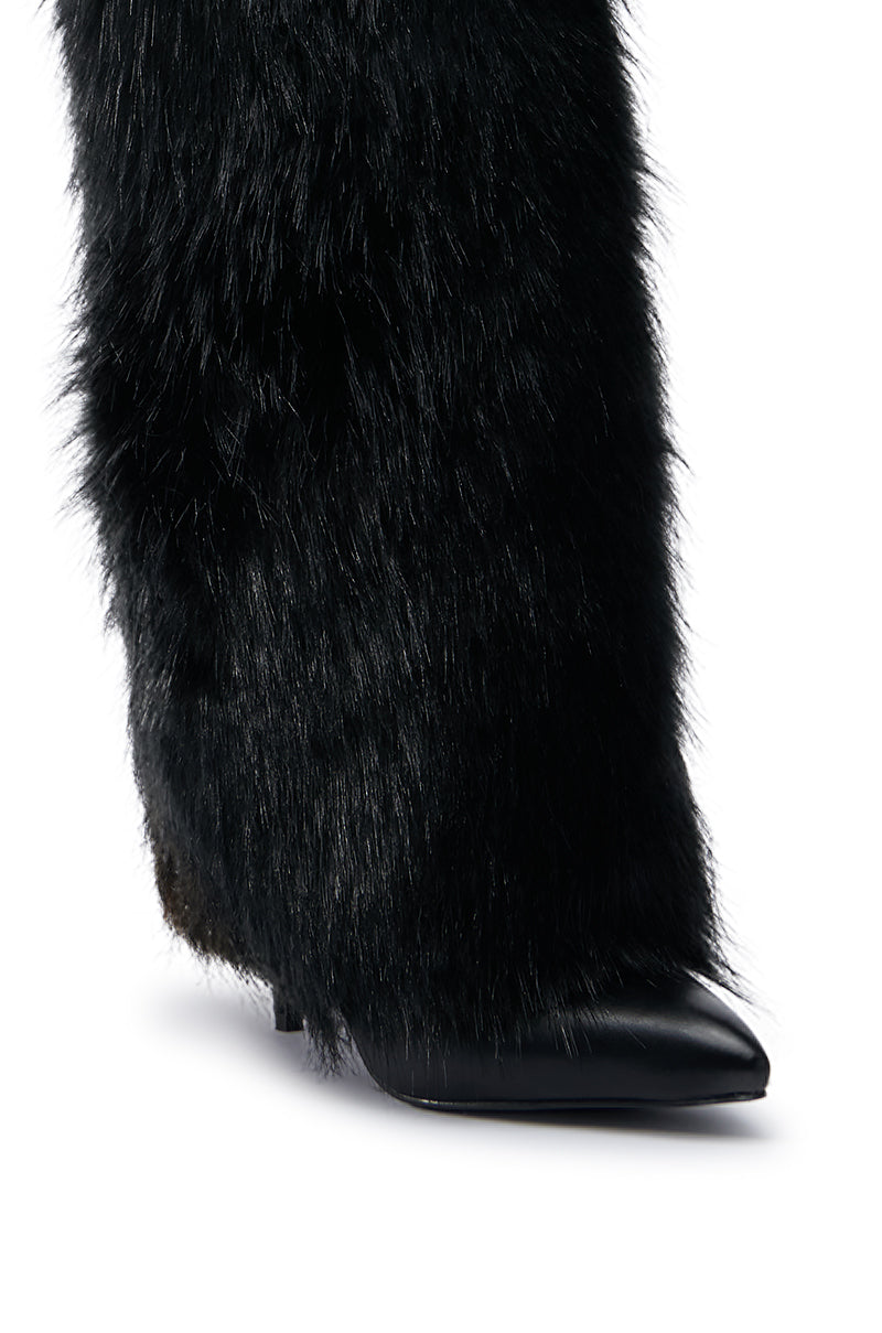 A close-up of the AZALEA WANG LANGDON BLACK BOOT showcases its black faux leather design, featuring a pointed toe and a low block heel. The boot's soft, fluffy texture covers nearly the entire surface, creating a striking contrast with its smooth, shiny tip.