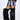 A person in a light purple faux fur mini skirt, matching bandeau, sheer black long-sleeve underlayer, and AZALEA WANG LANGLEYE BLACK THIGH HIGH FUR LUXE BOOTS stands against a plain white wall.