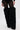 A person models the AZALEA WANG LANGLEYE BLACK THIGH-HIGH FUR LUXE BOOT—black lace tights and faux fur thigh-high boots with pointed stiletto heels—standing against a plain white background.