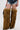 Someone wearing denim shorts and a black top models the AZALEA WANG LANGDON BROWN THIGH-HIGH FUR LUXE BOOT, featuring a shaggy, animal-like texture that covers the legs up to the thighs.