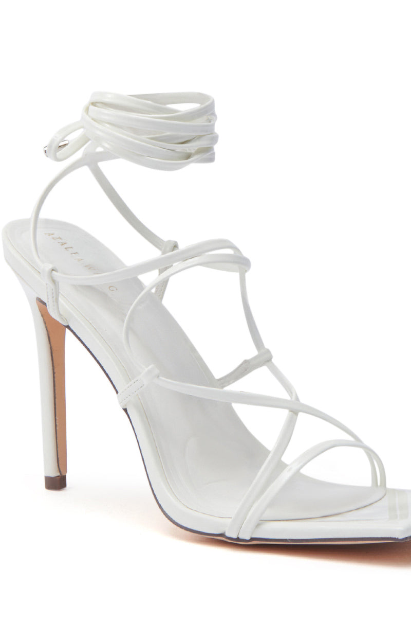 The AZALEA WANG LAURA WHITE STILETTO SANDAL features faux leather, thin adjustable straps, an ankle wrap design, and an open toe. Displayed on a white background.