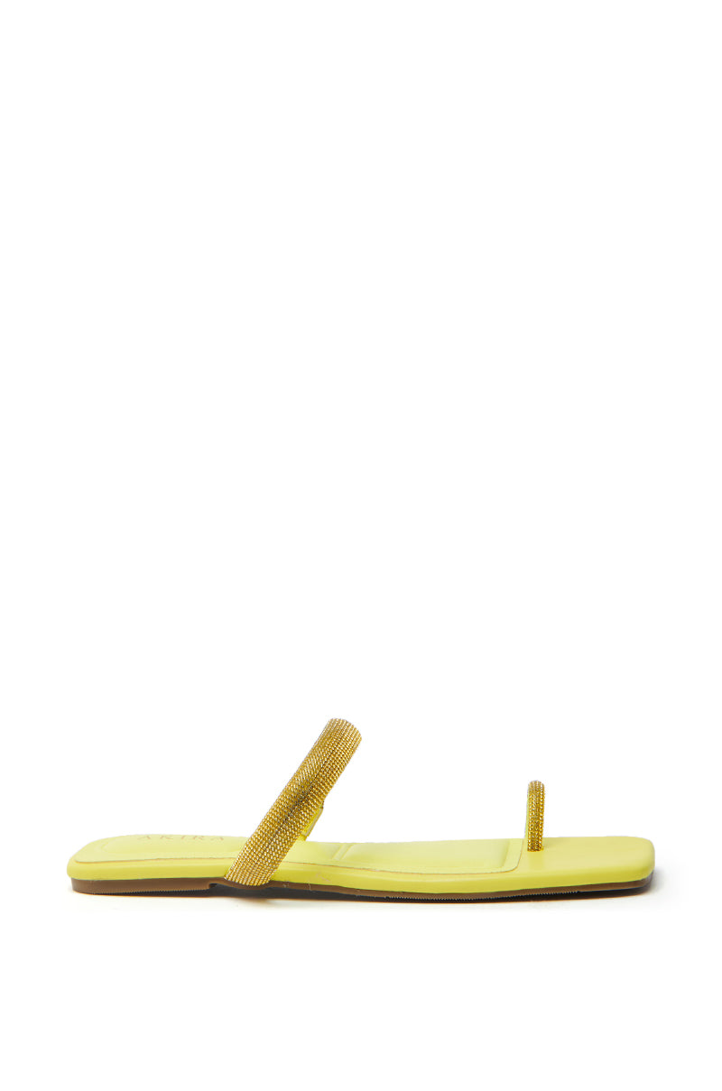 The AKIRA LAVEDA YELLOW EMBELLISHED FLAT SANDAL is a lime-yellow faux leather design featuring two thin, stud-adorned straps across the toes and arch, with a slightly squared toe for a minimalist yet stylish look.