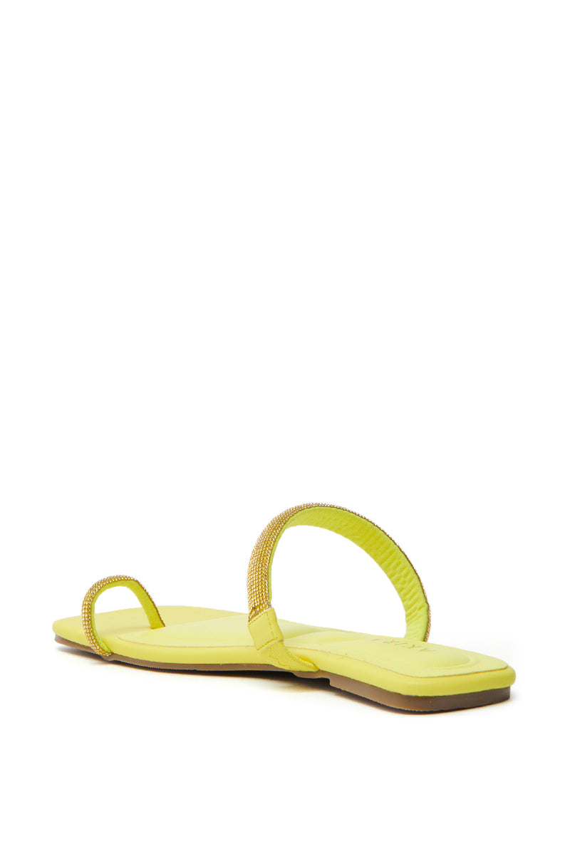 The AKIRA LAVEDA YELLOW EMBELLISHED FLAT SANDAL sports a light brown flat sole, faux leather design, and two thin straps in yellow—one with rhinestones around the toe and another near the ankle.