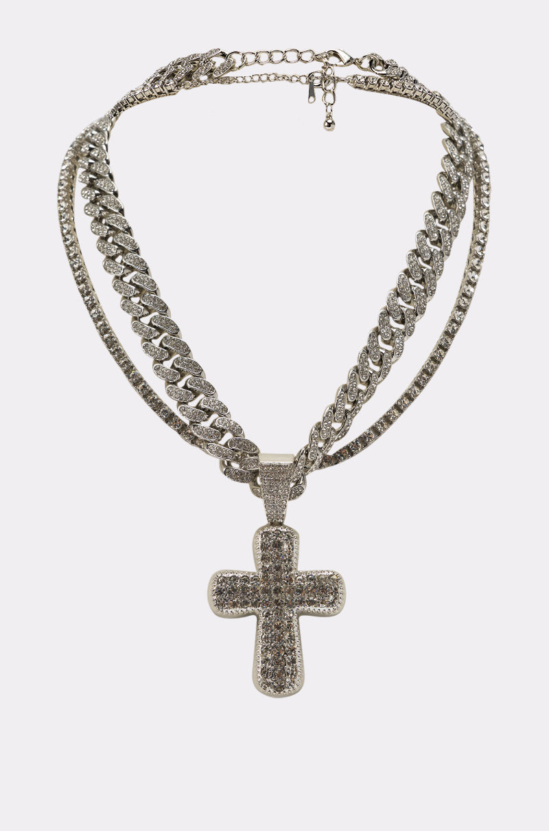 The GIMME NECKLACE is a layered set with a pavé Cuban link chain and a large rhinestone cross pendant, shown on a plain white background. 2