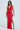 In a Sexy Can I Satin Maxi Dress, they showcase a stunning red, sleeveless satin gown that features a cowl neckline and thigh-high side slit. With long dark hair and a small clutch, they stand against an understated light background.