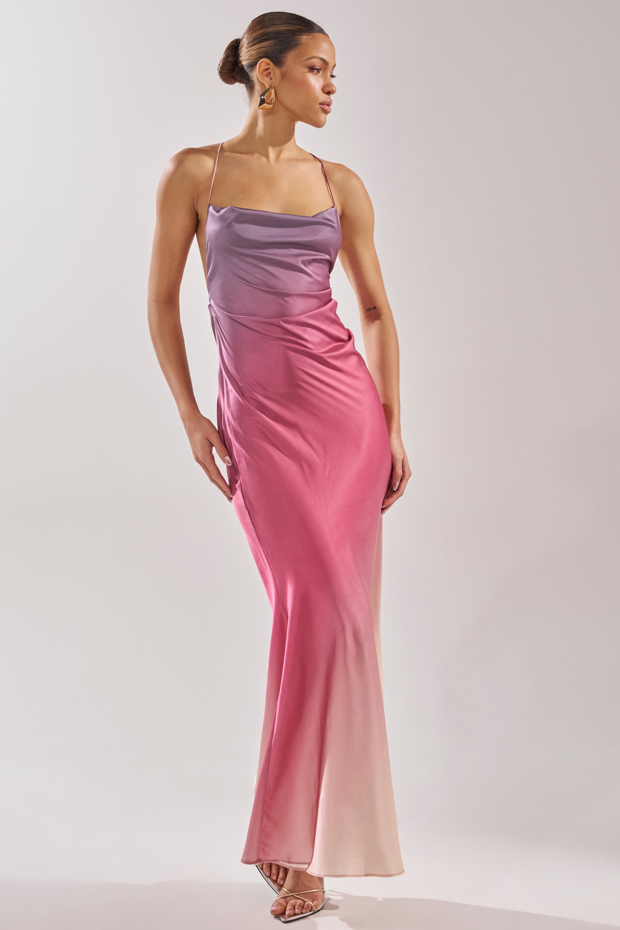 A woman models the PRETTY WOMAN MAUVE MAXI DRESS—a sleeveless, floor-length satin gown with thin straps and an ombre gradient from purple to pink and blush—against a plain background. 2