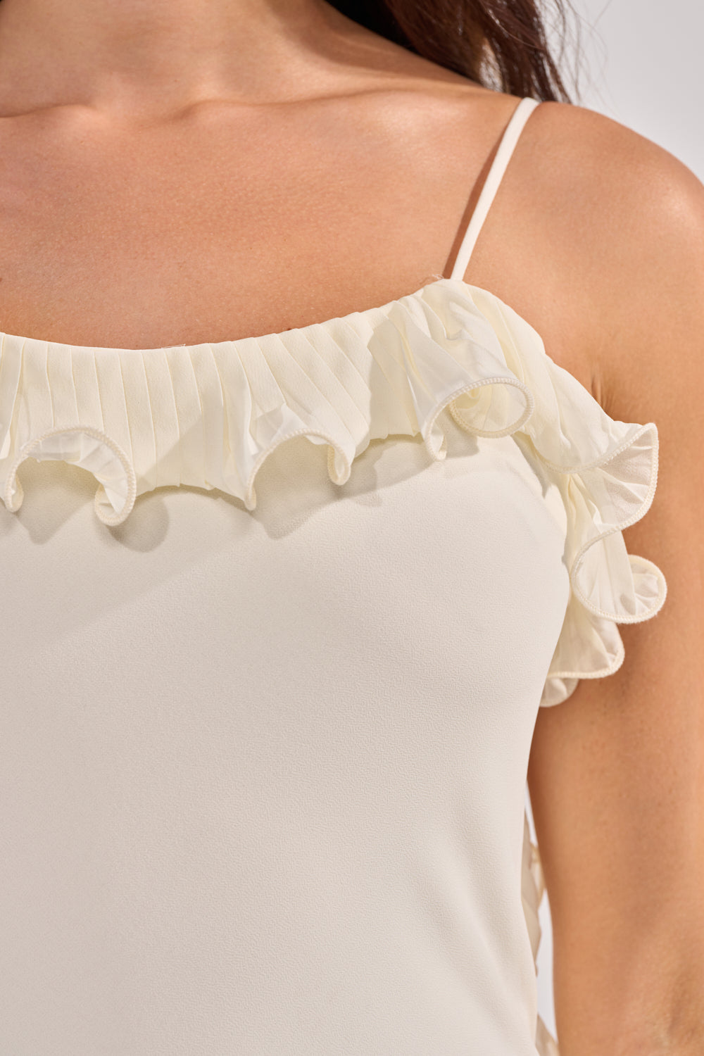Close-up of a woman in the LOVE ME OR LOSE ME RUFFLE MAXI DRESS IN IVORY, featuring thin straps and ruffled, pleated neckline. The lightweight, textured fabric makes it perfect for a bridal party dress. 4