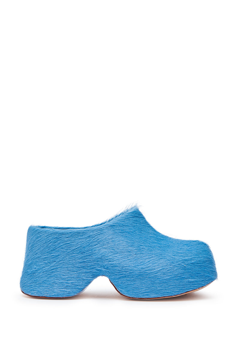The AZALEA WANG LEESHA BLUE PONY HAIR CHUNKY CLOG features a unique, sculpted flatform sole and a textured, fur-like blue surface, shown as a single shoe on a white background.