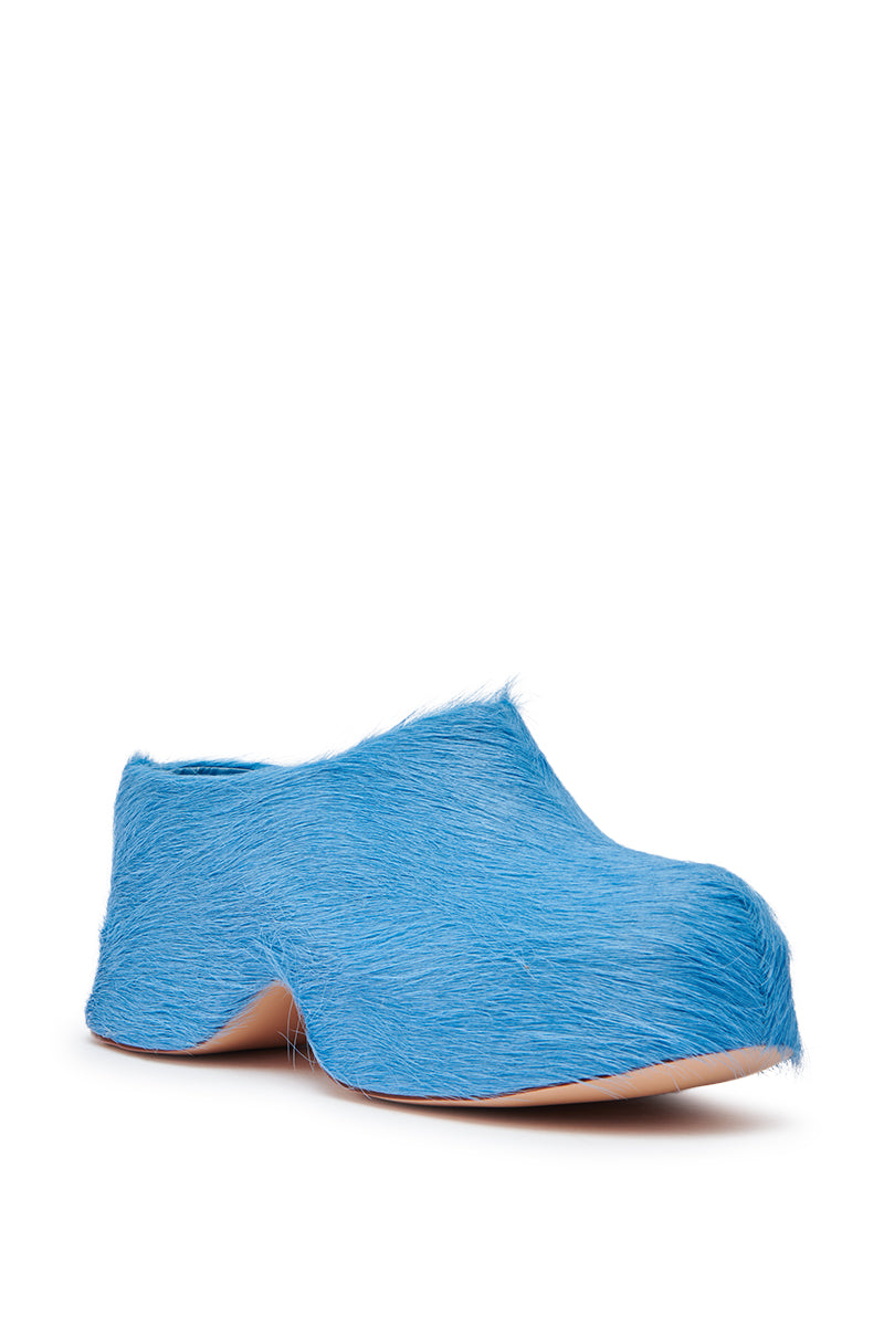 The AZALEA WANG LEESHA BLUE PONY HAIR CHUNKY CLOG features bright blue faux fur, a smooth tan sole, and a chunky heel, shown single on a white background.