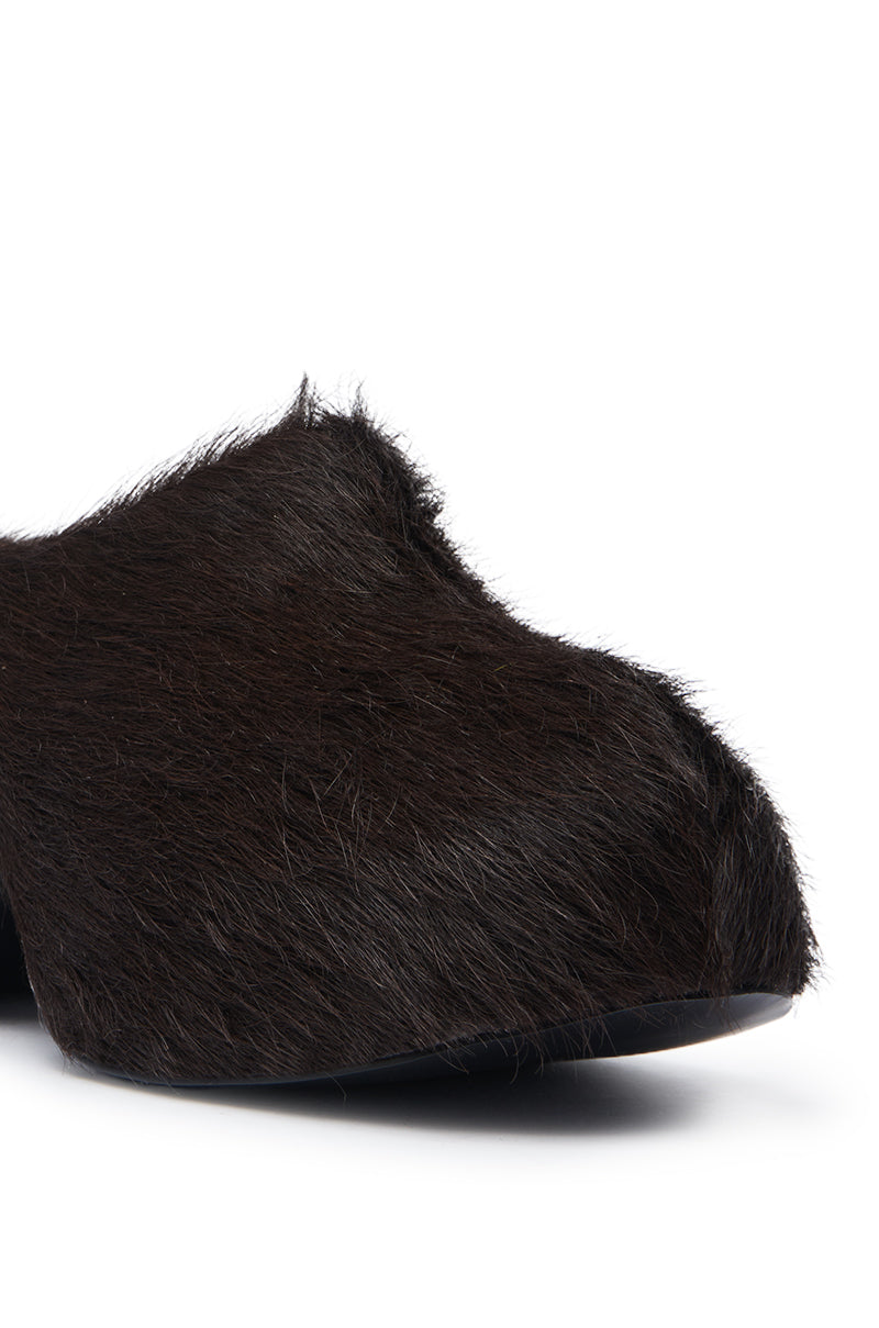 Close-up of the AZALEA WANG LEESHA CHOCOLATE PONY HAIR CLOG, featuring a dark brown shaggy fur-like texture and rounded toe; part of the sole is visible at the bottom.