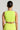 A person with their hair in a bun is seen from behind, wearing the SWEET AND SPICY TANK in a vibrant lime green, accessorized with hoop earrings and a necklace. The cropped silhouette stands out against a neutral background.