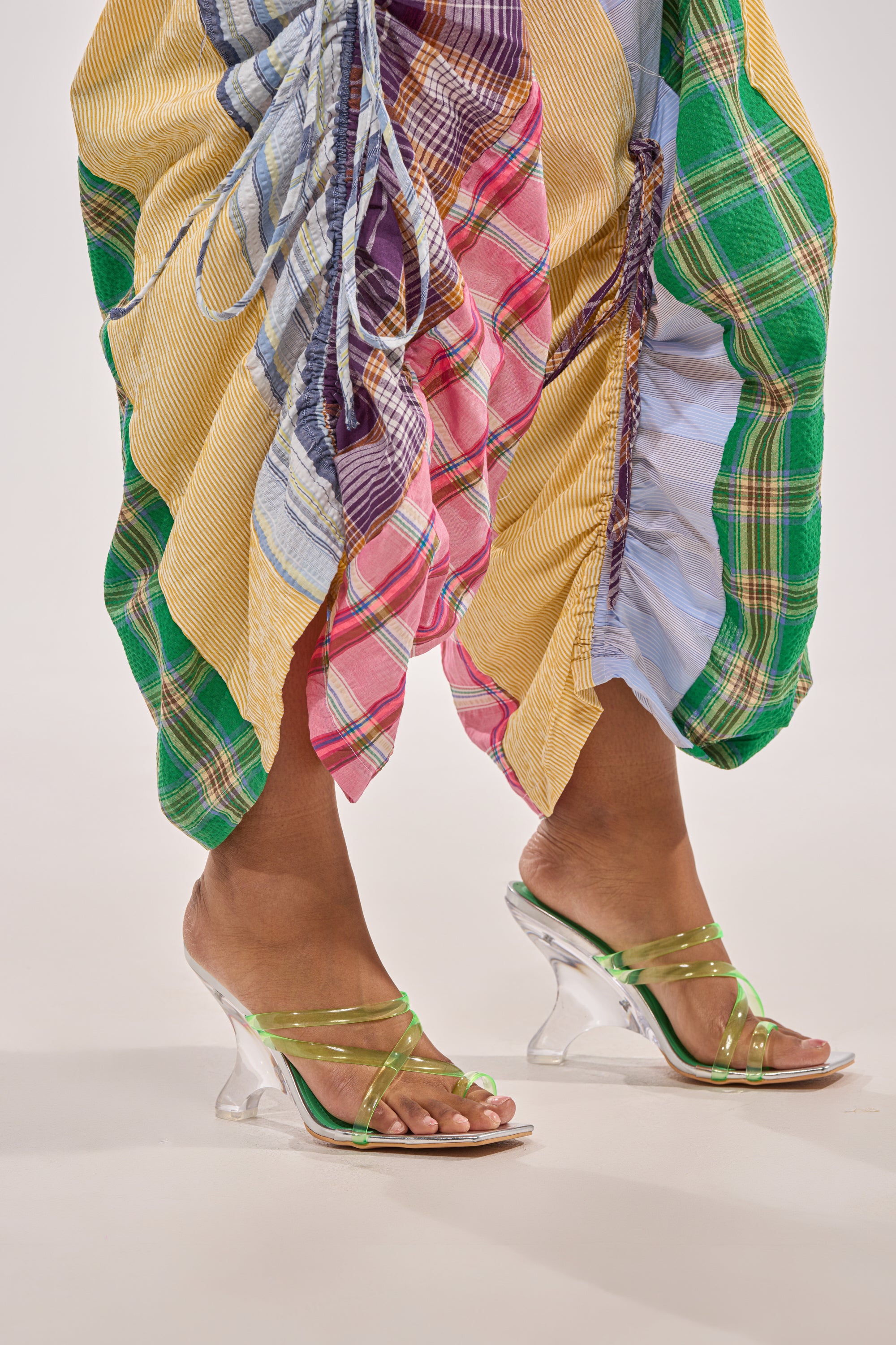 Person wearing a colorful patchwork skirt with gathered details and the AZALEA WANG LEMUEL GREEN AND SILVER WEDGE SANDAL, standing on a light background. 2