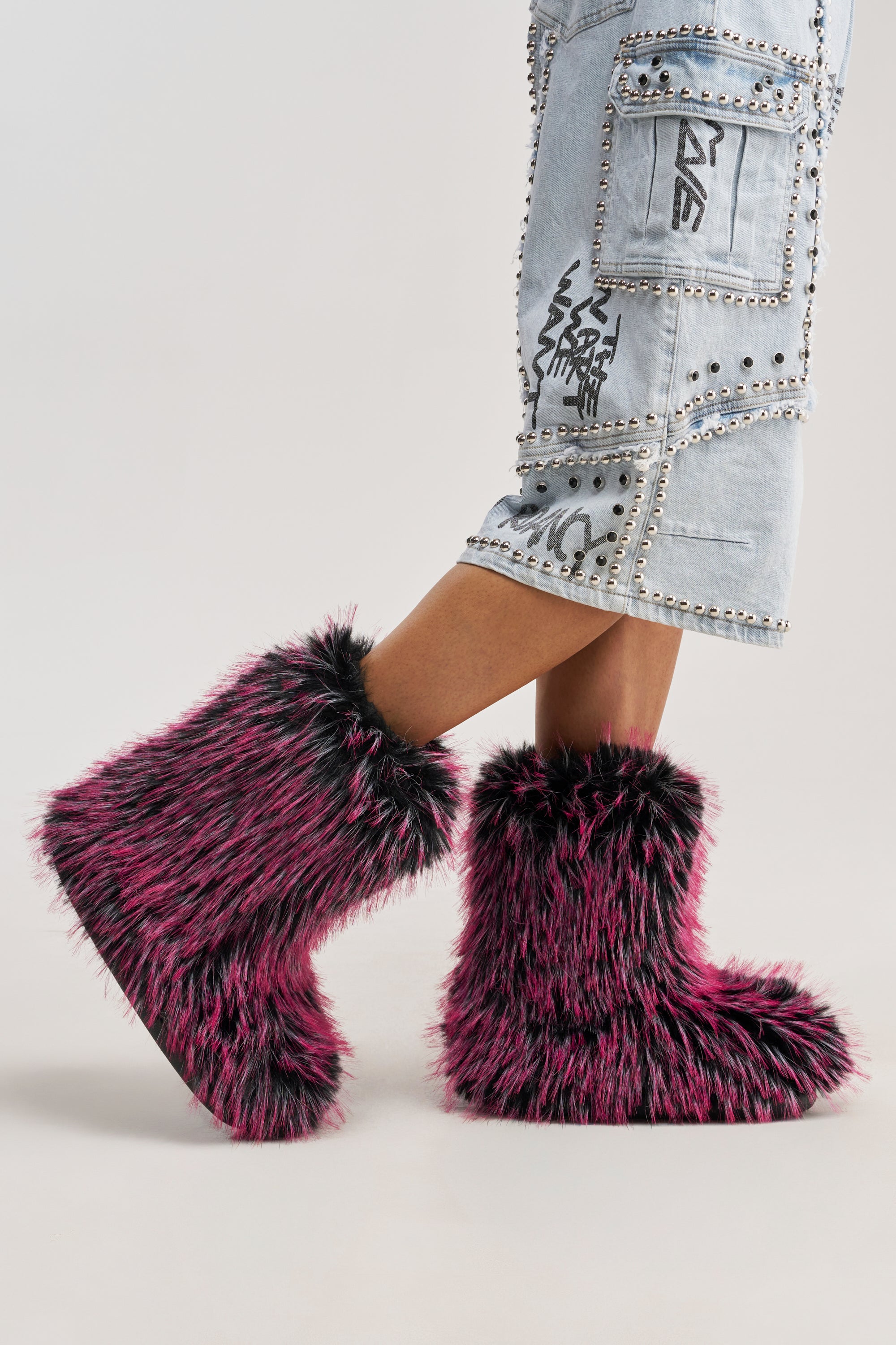 A person in the AZALEA WANG LENIX PINK MULTI FLAT FUR BOOTIE and light blue denim patchwork shorts stands against a plain light background.