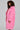 A person with curly hair stands sideways, showcasing the LENOX FAUX FUR TRENCH IN PINK. The plain gray background emphasizes the vibrancy and high-quality faux fur of the oversized coat.