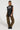 A person with braided hair stands confidently, wearing a sleeveless top featuring text and fringe details. They pair it with THE ULTIMATE LEOPARD CARGO PANT and black shoes, creating a relaxed silhouette against the plain white background.