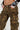 A person showcasing a relaxed silhouette in THE ULTIMATE LEOPARD CARGO PANT and a long-sleeve shirt with a tattoo-style design, hands casually tucked in pockets. The photo highlights the bold pattern of the pants and the laid-back pose.