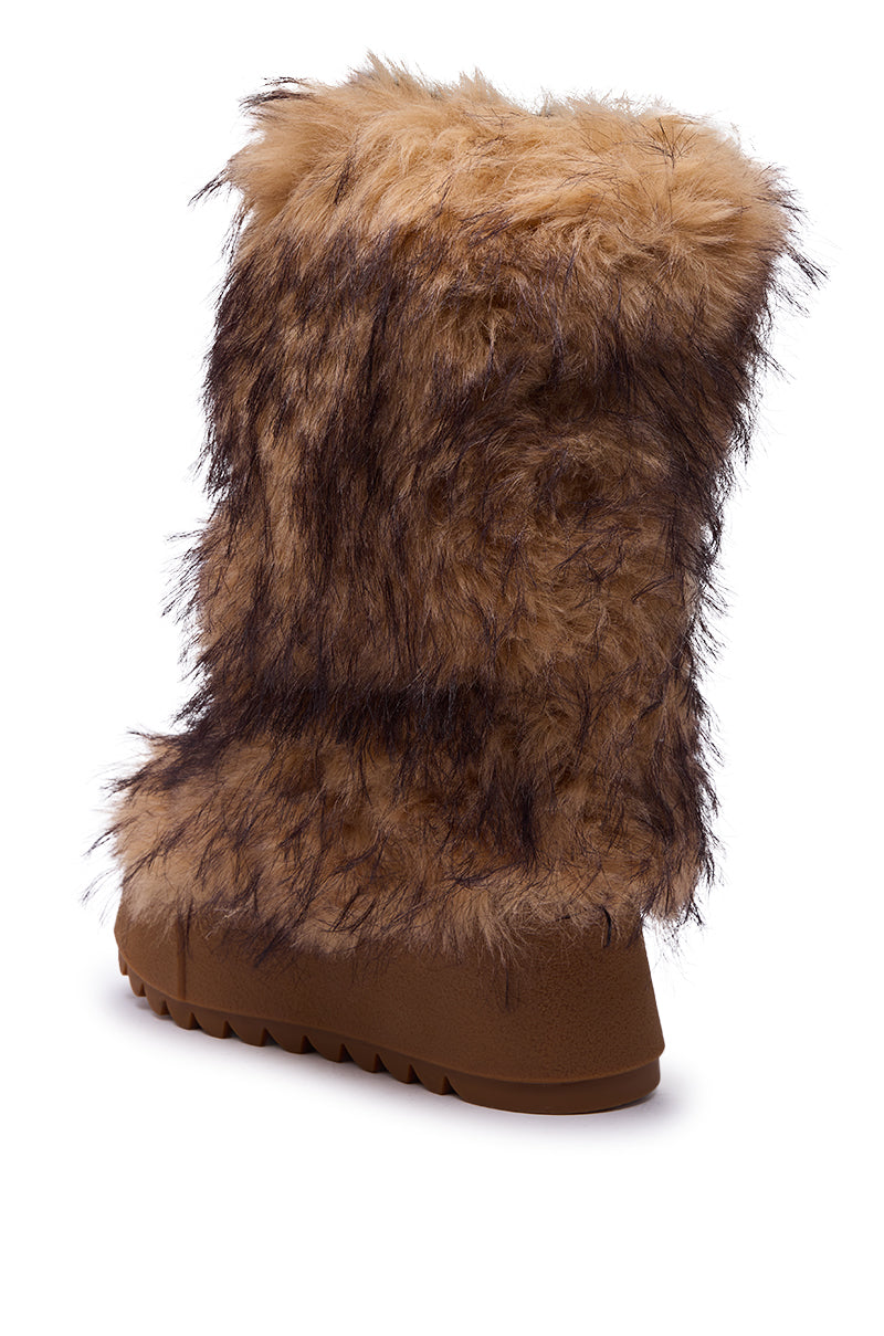 The AZALEA WANG LEOPOLD BROWN MULTI FLAT FUR BOOT features tan and brown faux fur with darker streaks and a rugged, ridged platform sole. Its fluffy, textured look is highlighted from a back and side angle.
