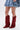 Wearing a short, flared light denim skirt and the AZALEA WANG LETTICE BURGUNDY FAUX SUEDE WESTERN BOOT with a chunky heel, this person holds a matching denim bag while standing against a plain background.