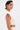 A woman with short dark hair stands in profile, wearing the SYDNEY TEXTURED BLOUSE and matching bottoms. She accessorizes with a nose ring, bold silver earrings, and a red linear upper arm tattoo for a chic look.