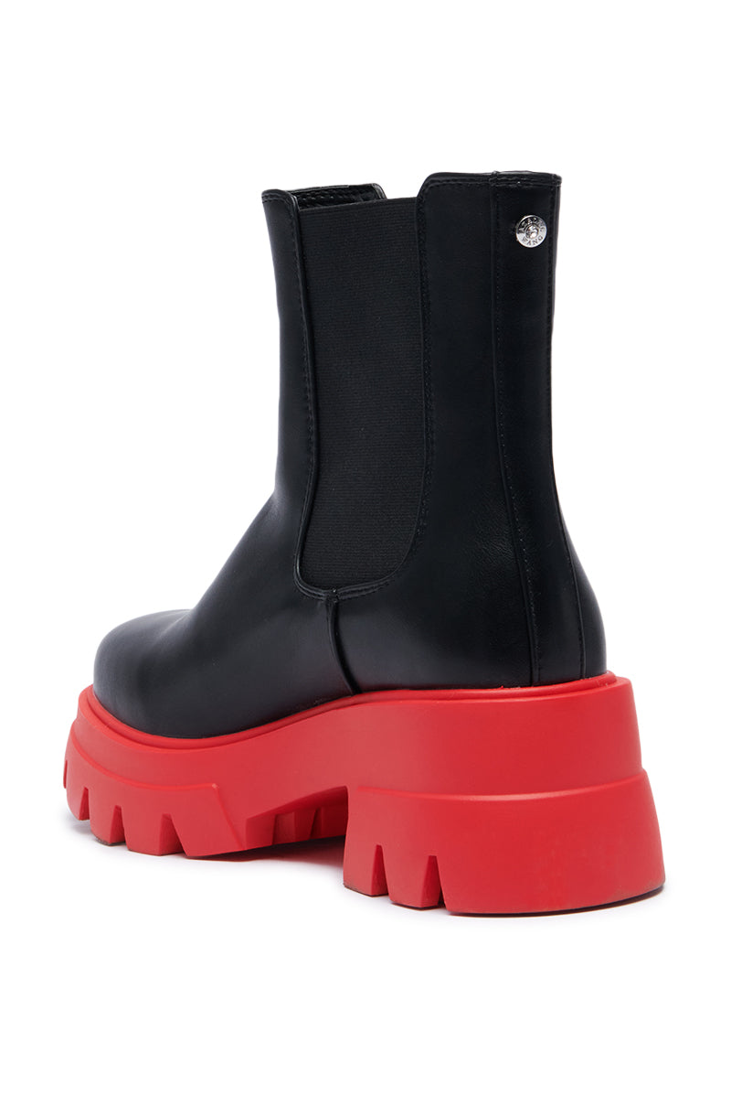 The AZALEA WANG LINDIE BLACK BOOTIE, crafted in sleek faux leather, features striking black chunky platform lug soles. It includes an elastic side panel and a subtle round silver detail near the top, creating a bold contrast against a plain white background.