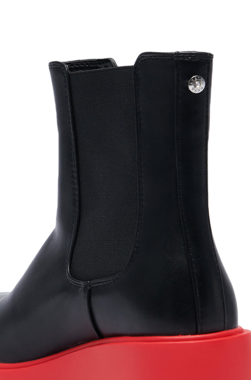 Close-up of the AZALEA WANG LINDIE BLACK BOOTIE, a black faux leather Chelsea boot with an elastic side panel and a striking red sole. A small decorative metal stud is present at the top of the boot, enhanced by a fashionable platform lug sole for added style.
