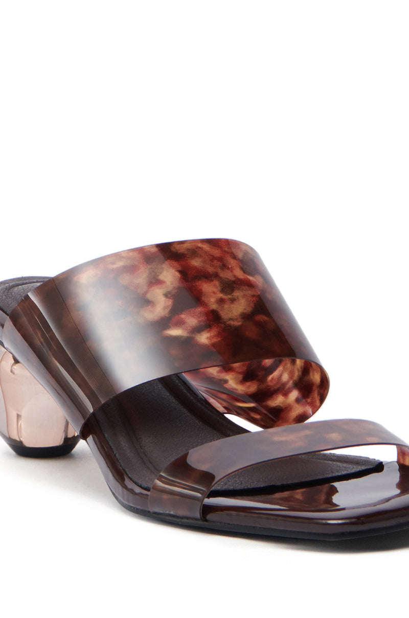 The AZALEA WANG LIRIO BROWN BALL HEEL SANDAL sports wide, glossy faux patent leather straps in dark red marbled hues with an open toe design. A distinctive novelty transparent heel adds a modern flair to this chic footwear.