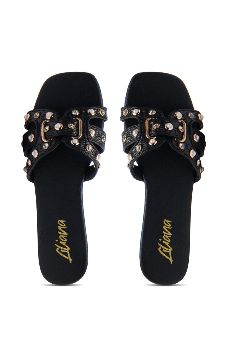 The LISA BLACK EMBELLISHED SLIP ON SANDAL features black straps with gold and silver studs and decorative buckles. An open square toe design with "Liliana" in gold script on each footbed, these sandals make a striking addition to any outfit.