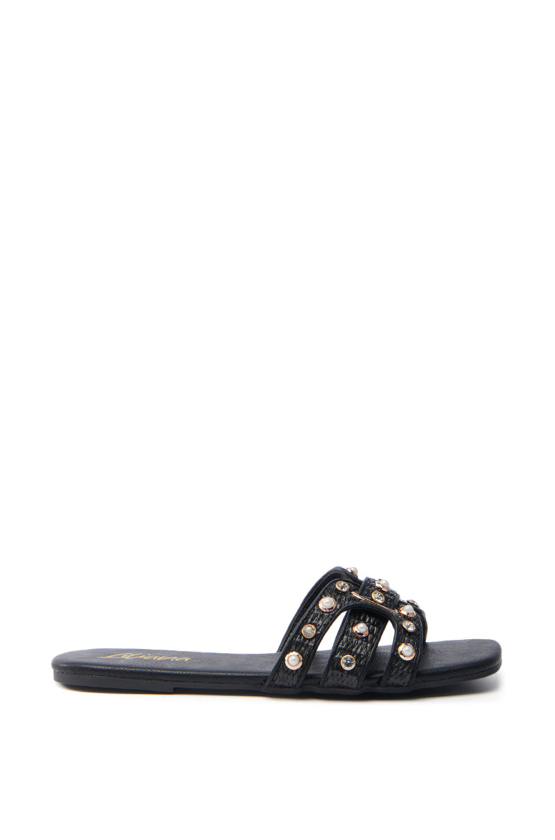 The LISA BLACK EMBELLISHED SLIP ON SANDAL, showcased against a white background, features an open square toe and three thin straps adorned with shiny silver studs. Its elegant design includes a flat sole, providing a modern twist to classic simplicity.
