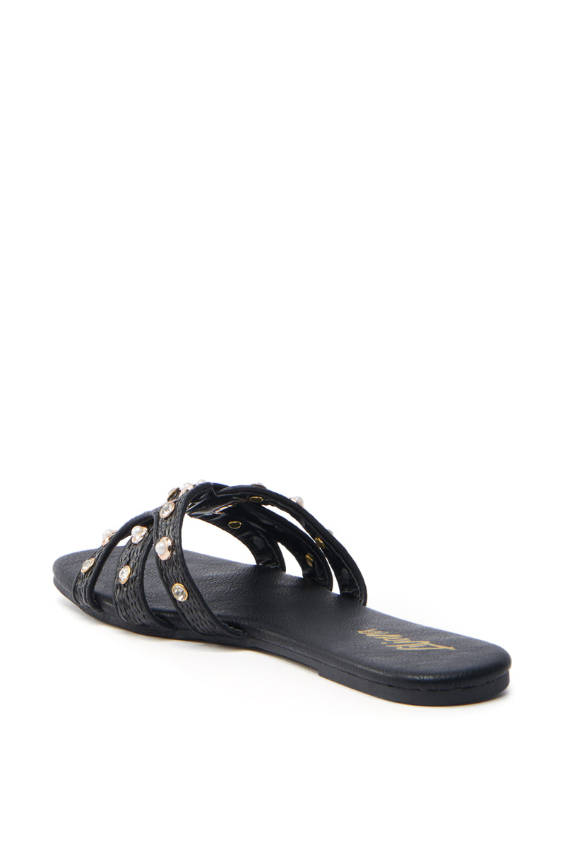 The LISA BLACK EMBELLISHED SLIP ON SANDAL features crisscross straps with silver studs, an open square toe, a sleek textured finish, and a cushioned footbed for comfort.