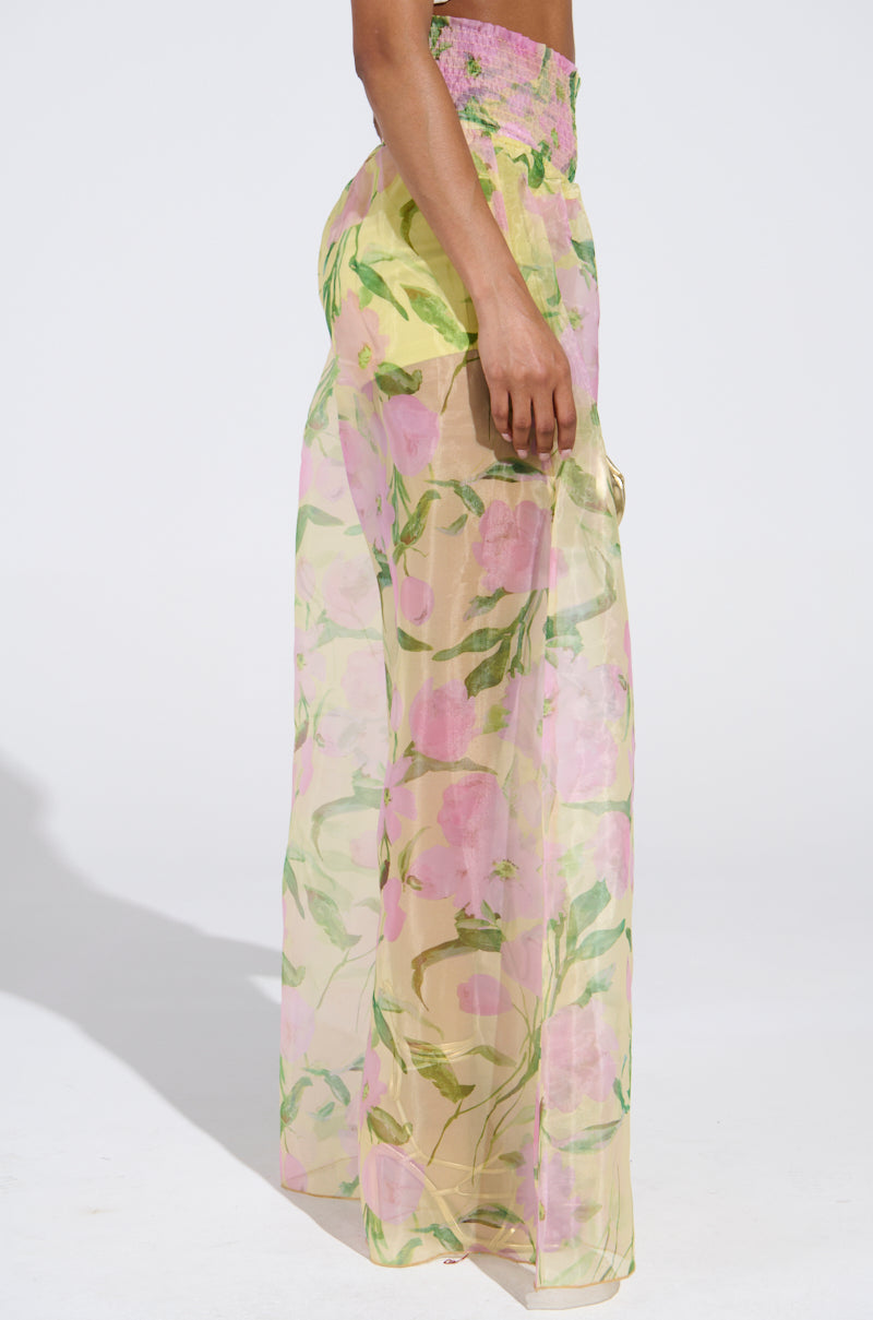 A person wearing the FLOWER POWER WIDE LEG PALAZZO PANT, featuring a pink and green floral print. The chiffon fabric adds elegance, visible from a side view extending from waist to feet against a plain background.