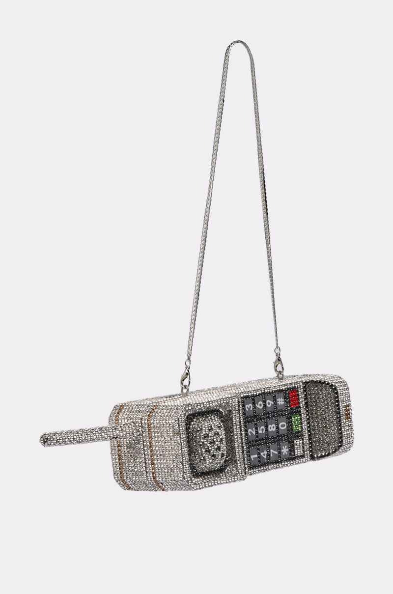The CALL ME BLING CLUTCH is a phone-shaped purse styled like a vintage brick cell phone, featuring sparkling rhinestones, a long chain strap, and a detailed keypad on the front. 7