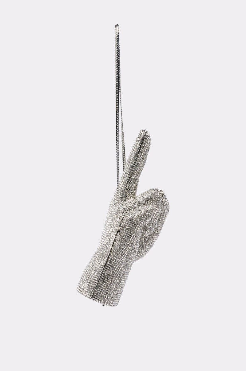 The PEACE BLING PURSE is a sparkling silver rhinestone handbag shaped like a hand with a raised peace sign, hanging by a thin strap against a light background—unique and perfect for any occasion. 4