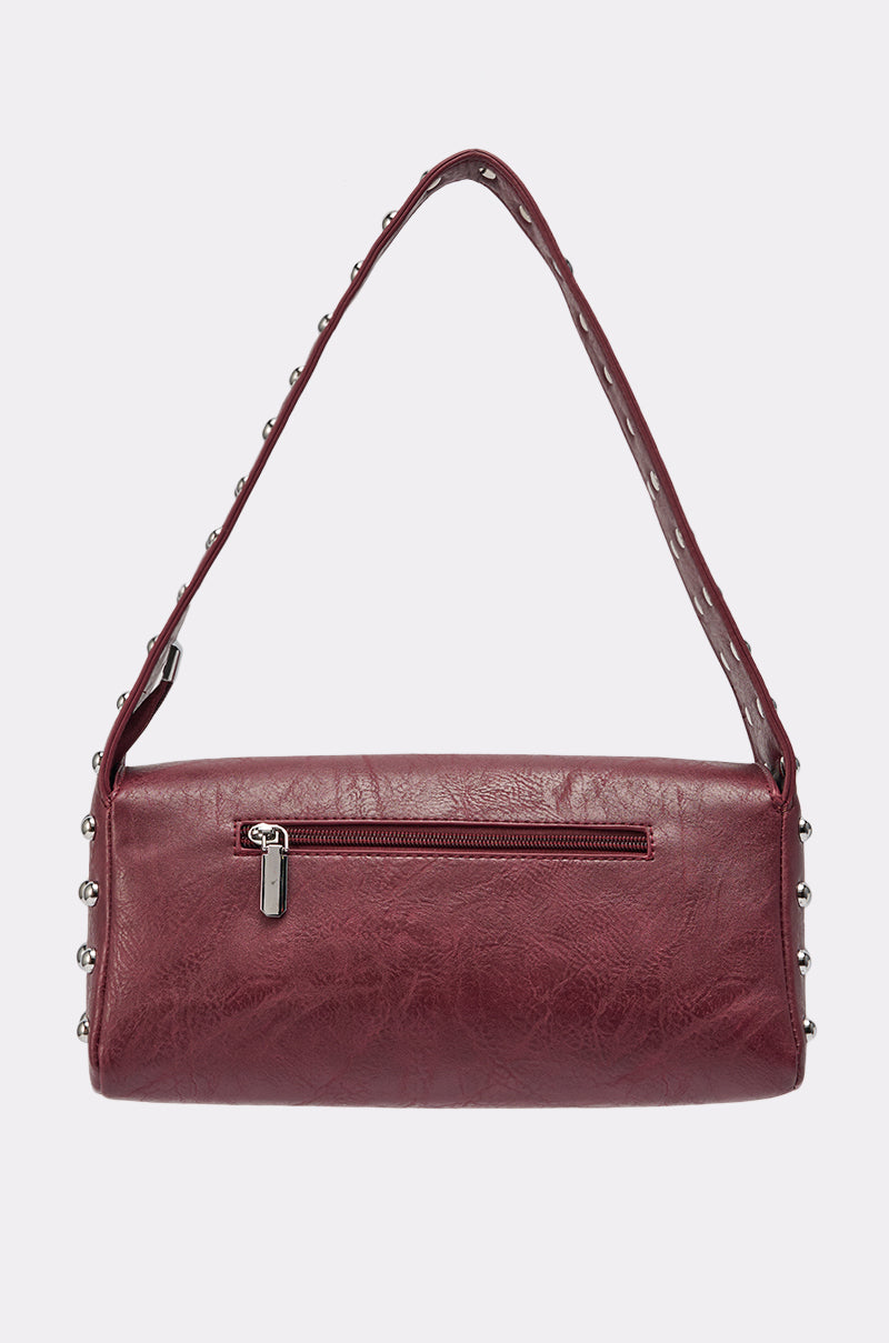 The LOLA STUDDED PURSE is a maroon leather shoulder bag with a single studded strap, front zipper pocket, and a sleek rectangular shape. 3
