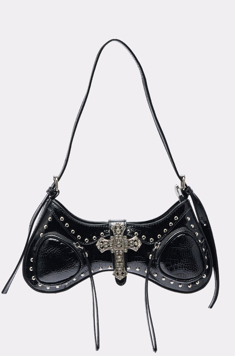 The HEAVEN SENT PURSE is a black patent faux leather shoulder bag with a single strap, featuring crocodile print, silver stud accents, ribbon details, and a large decorative silver cross at the center. 0