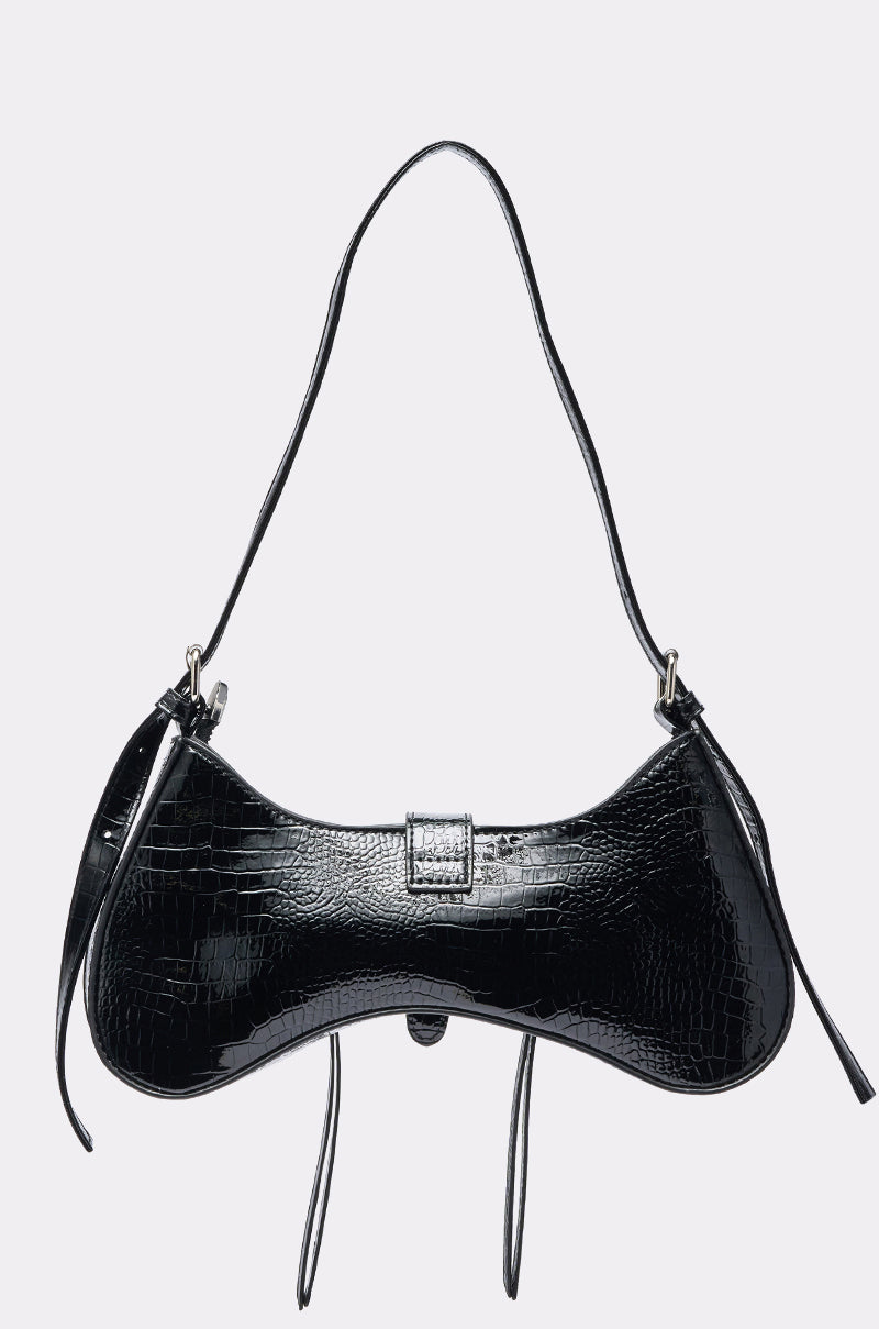 The HEAVEN SENT PURSE, in black crocodile print faux leather, features a curved shape, thin long shoulder straps, and a central buckle, displayed against a plain light gray background. 3