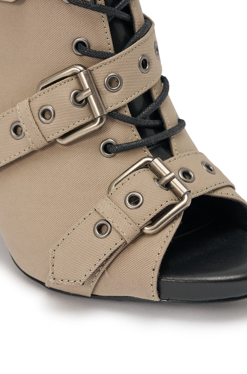 Close-up of the AZALEA WANG LOOM TAUPE OPEN TOE BOOTIE, featuring beige canvas, metal eyelets, two silver buckles, black laces, a chunky block heel, open-toe mule design, and sleek fabric finish. 5
