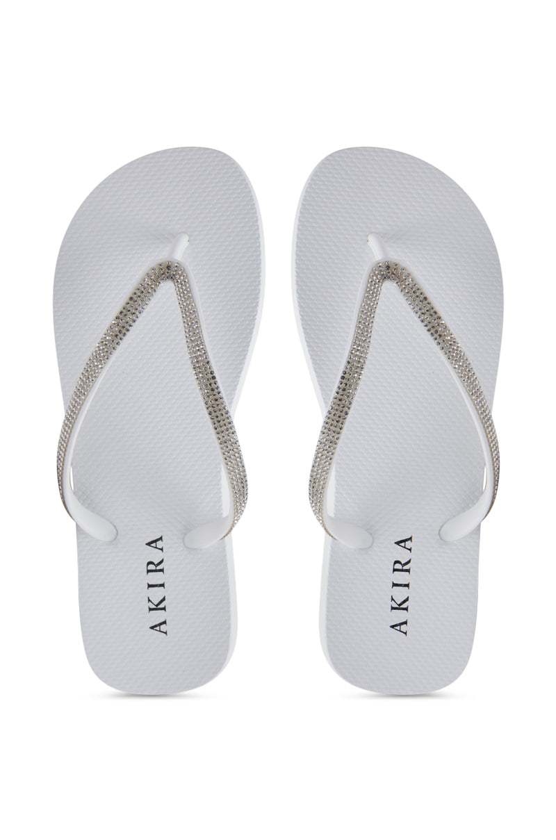 The AKIRA LORETA WHITE THONG FLIP FLOP features rhinestone-adorned silver beaded straps and the "AKIRA" brand name printed on the footbeds.