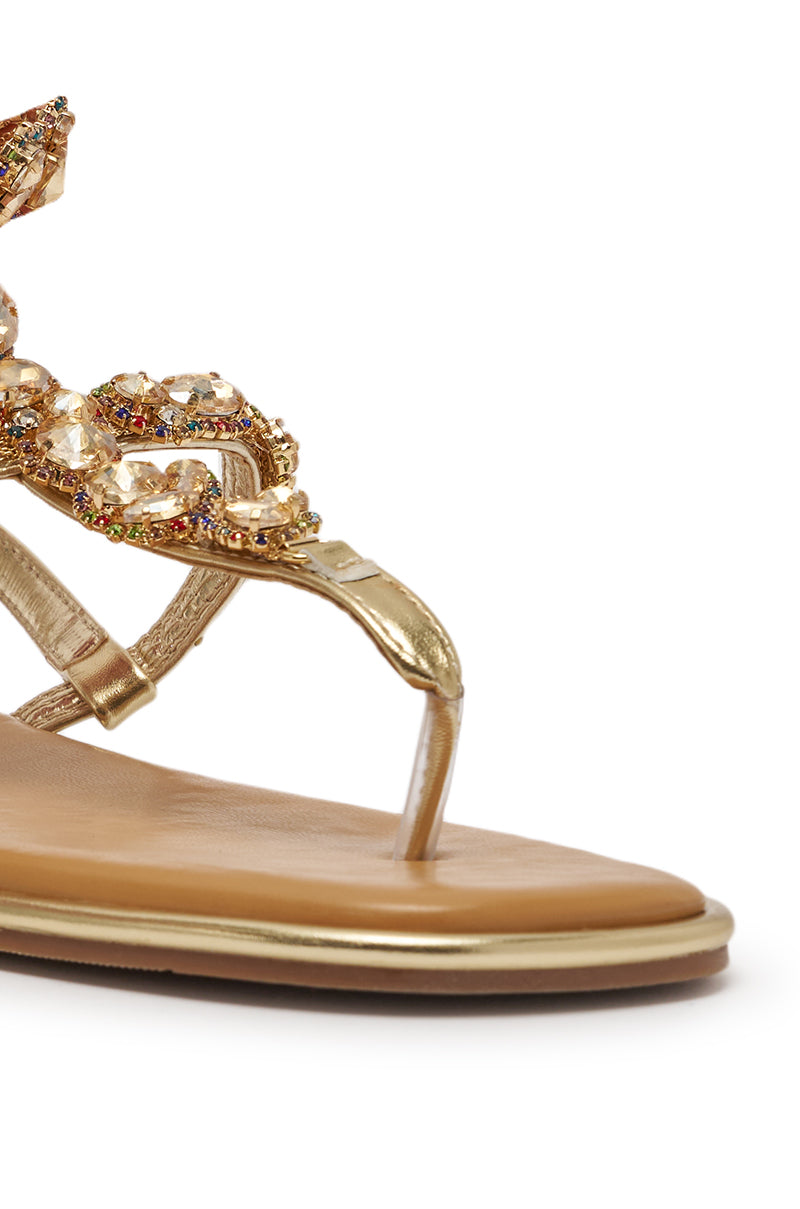 Close-up of the AZALEA WANG LOSKI Gold Metallic Sandal featuring a tan footbed and rhinestone-embellished T-strap adorned with sparkling crystals and colorful gemstones. 5