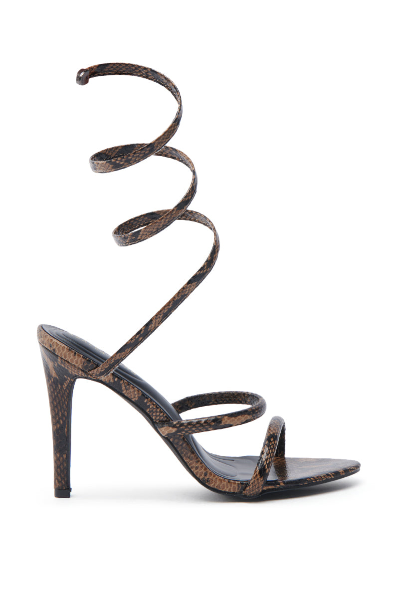 The AKIRA LOWRI BROWN SNAKE SPIRAL STILETTO SANDAL is a sleek vegan leather sandal with a brown and black snakeskin print, featuring an open toe, two front straps, and a spiral ankle strap with slender heels.