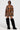 The person is wearing a brown-striped jacket with the MESS AROUND MINI SKIRT, complemented by tall black furry boots and a sleek black top. Sunglasses add a touch of mystery as they pose confidently against the plain white background.
