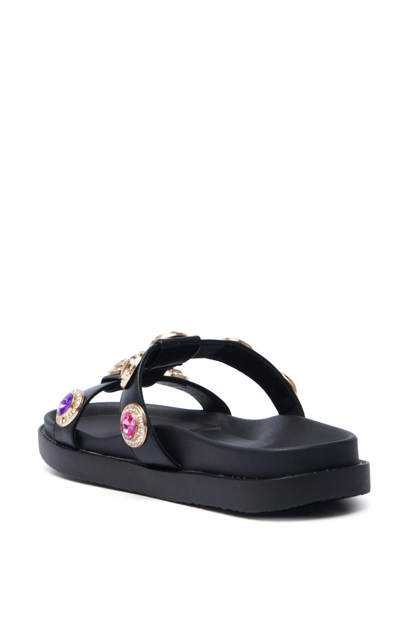 The AZALEA WANG LUCIENA BLACK RHINESTONE SANDAL features a thick sole with two jeweled straps decorated in purple and pink gems. Made from vegan leather, it's displayed on a white background to showcase its elegant side and back view.