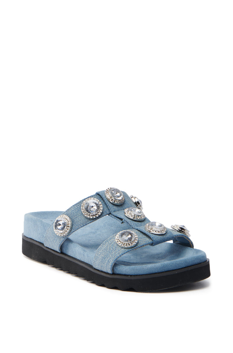 The AZALEA WANG LUCINEA DENIM RHINESTONE SANDAL features chic wide blue straps with large round rhinestones, a soft footbed, and a grooved black sole for style and grip.