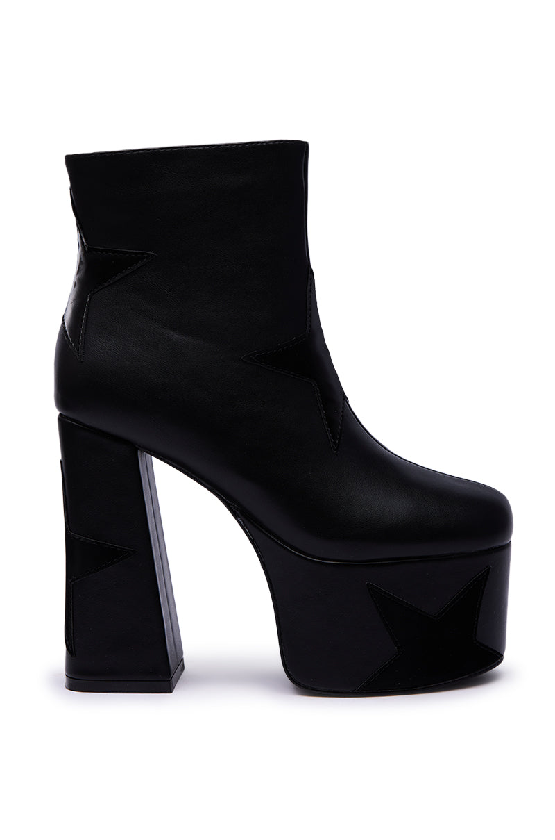 The AZALEA WANG LUKYIE BLACK STAR DETAIL PLATFORM BOOTIE is a black faux leather bootie with a tall, chunky rectangular heel and star-shaped accents on the side and heel.