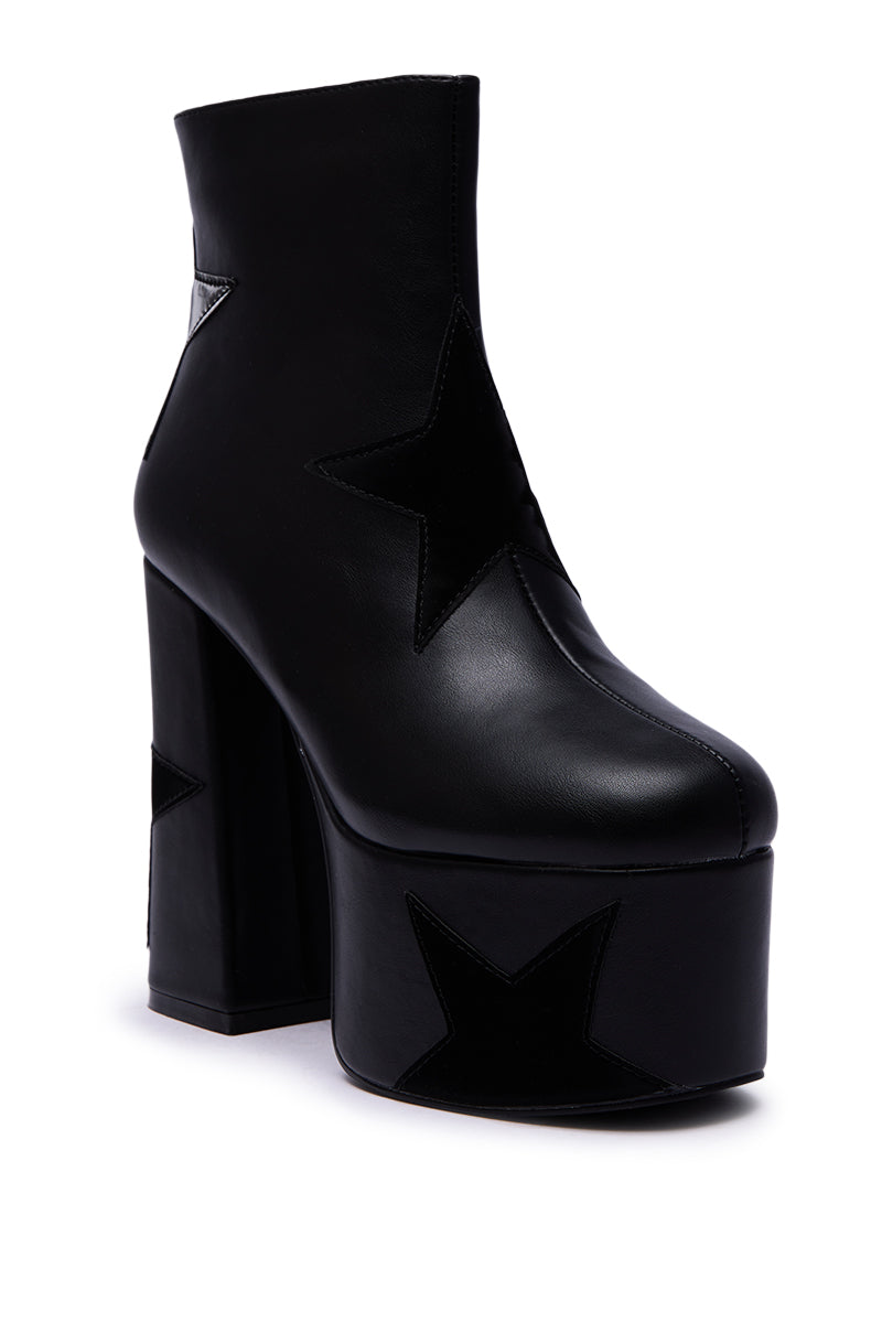 The AZALEA WANG LUKYIE BLACK STAR DETAIL PLATFORM BOOTIE is a black platform bootie with a chunky heel and bold black star-shaped patches on the side and platform.