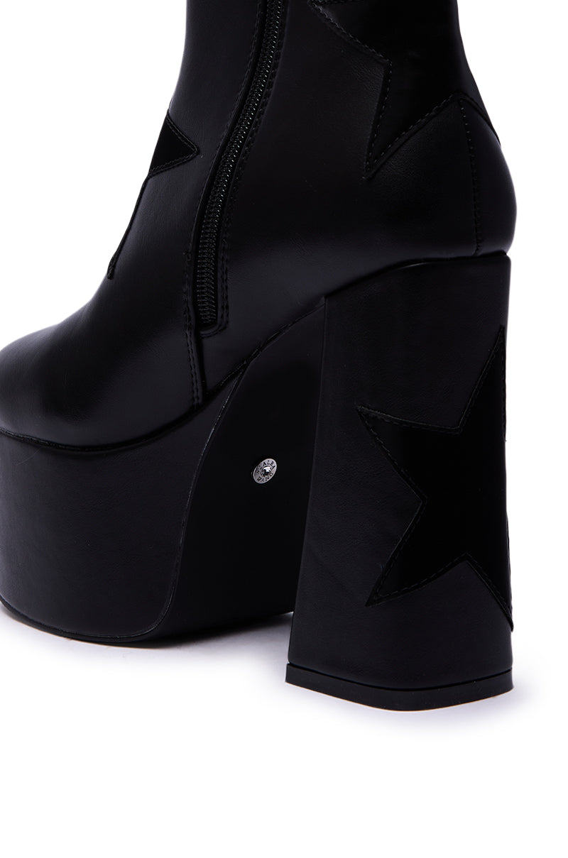 The AZALEA WANG LUKYIE BLACK STAR DETAIL PLATFORM BOOTIE features a high black faux leather design with star-shaped details, a chunky heel, and a side zipper.