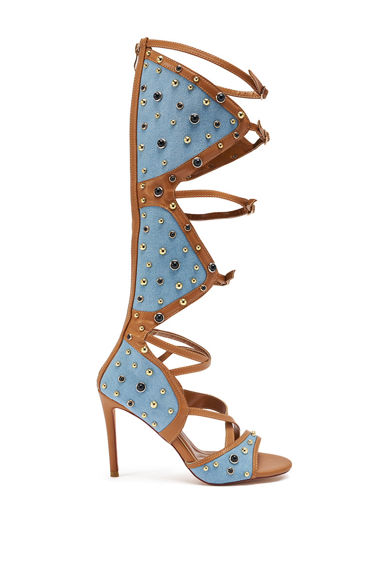 The AKIRA GOLD LULANA DENIM METAL STUDDED GLADIATOR STILETTO SANDAL features tan leather straps, blue denim panels with gold and silver studs, an open toe, and a knee-high stiletto heel. 5