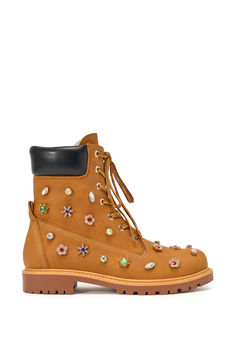 The AKIRA GOLD LUSTER TAN EMBELLISHED FLAT COMBAT FESTIVAL BOOTIE features tan suede, a black padded ankle collar, tan laces, multicolored rhinestone embellishments, and a rugged brown sole for standout streetwear style. 4