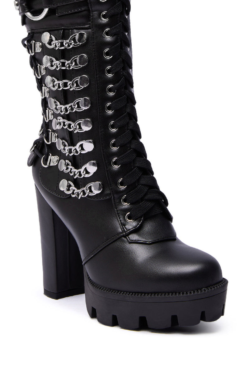 The AZALEA WANG LUUK BLACK METAL HARDWARE EMBELLISHED CHUNKY BOOTIE features black faux leather, a high heel, chunky tread, lace-up front, and bold silver hardware chains for an edgy statement look.