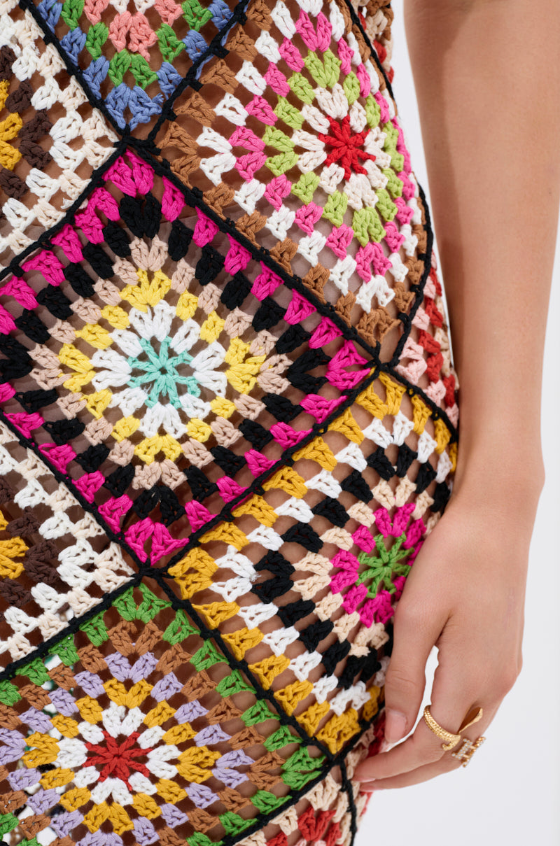 Close-up of a hand with rings resting near the hip, highlighting the playful, beach-ready vibe of the DONT LET ME GO CROCHET MAXI DRESS, featuring vibrant multicolored square patches.